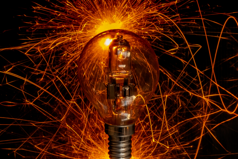 Image of a light bulb with orange lights in the background imitating electricity