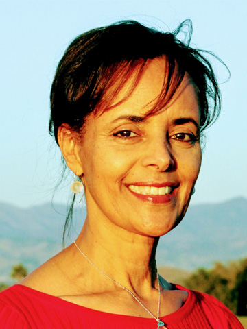 Senait Forthal with sun on her face and green hills in the background.