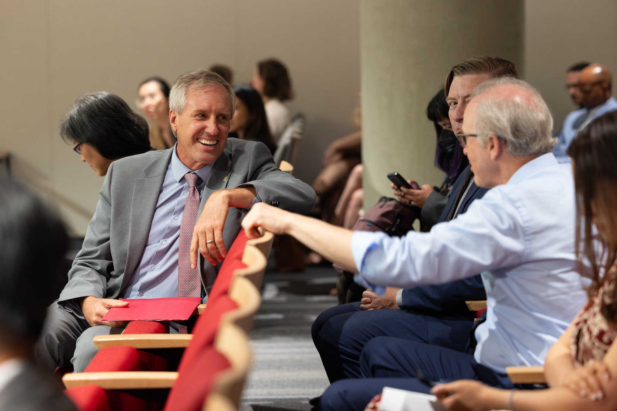 Photo of Chair David Hochschild sitting and speaking with an unidentified person. 