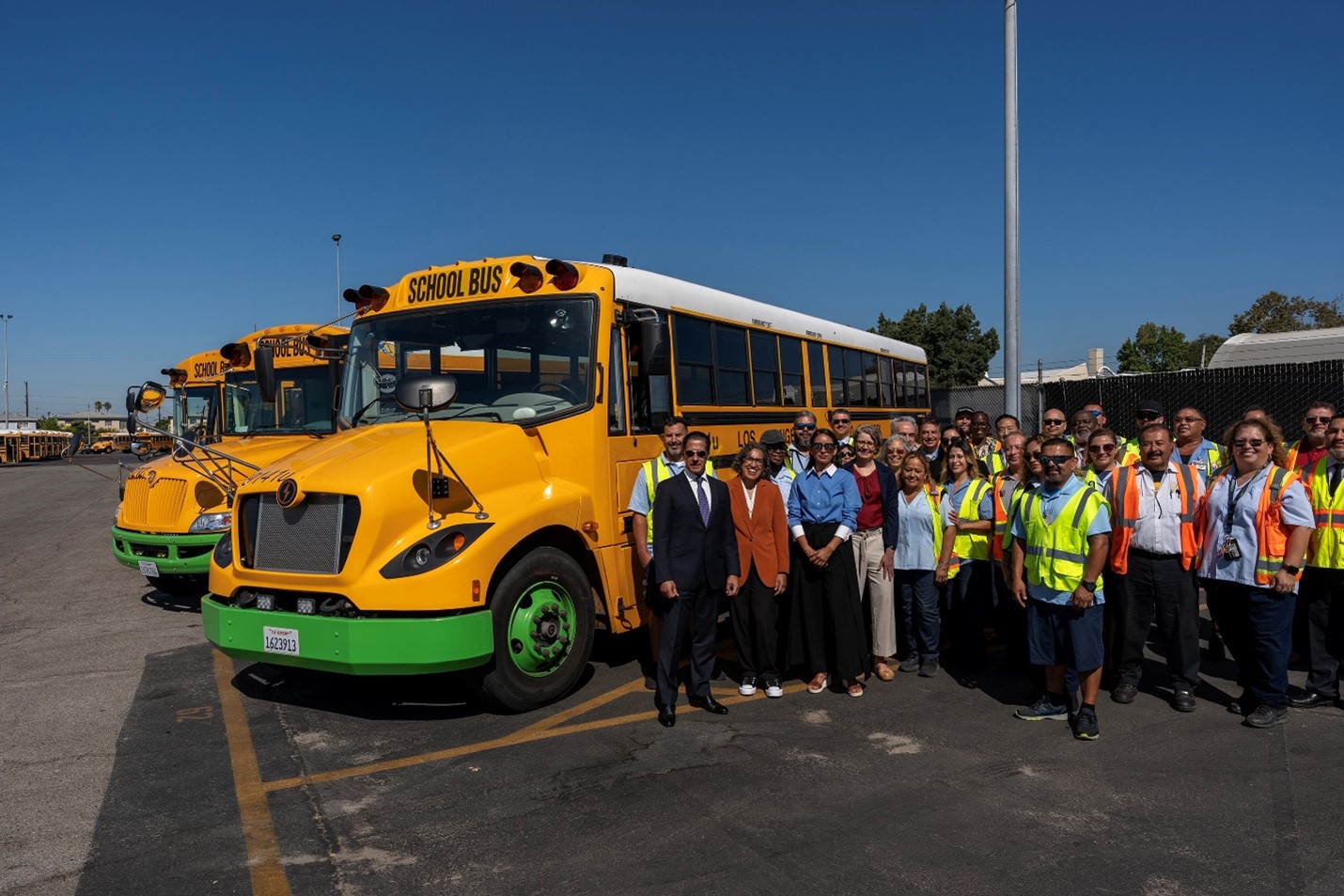 Photo of people standing next to a zero emission school bus. 