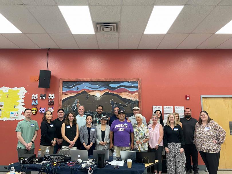 Chemehuevi Tribe and California Energy Commission Staff standing behind a table with laptops and broadcasting equipment. 