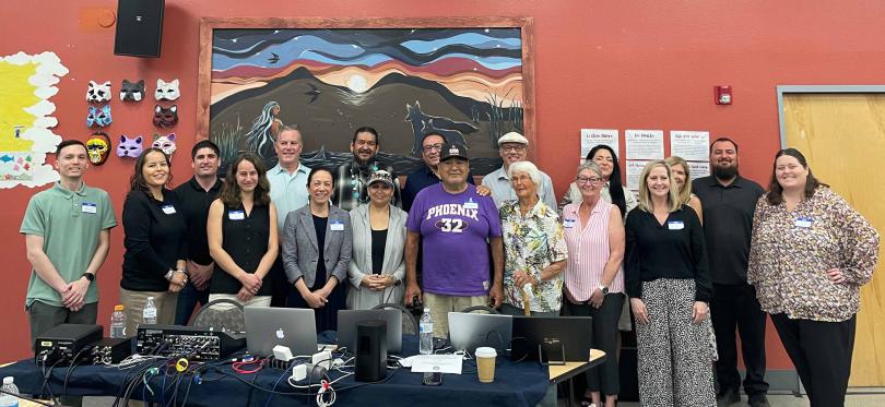 Chemehuevi Tribe and California Energy Commission Staff standing behind a table with laptops and broadcasting equipment. 