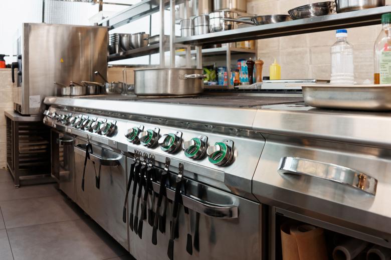Commercial flattop and range, with utensils hanging from oven handles