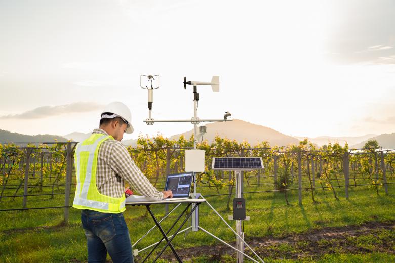 Agronomist using tablet computer collect data with meteorological instrument to measure the wind speed, temperature and humidity and solar cell system in grape agricultural field, Smart farm concept.