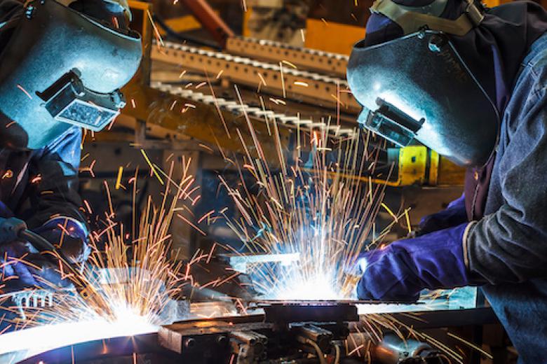 Picture of two people welding in an industrial facility.