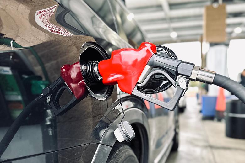 Gasoline pump nozzle being inserted into vehicle