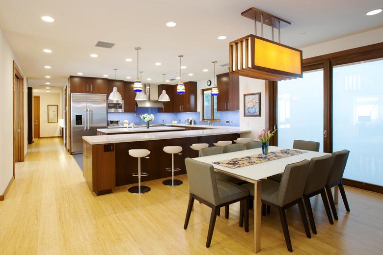 U shaped kitchen with island, with hallway and openign to left. Refrigerator and stove on back "U" leg  and sink to the right below window, front "u: leg counter with bar seating.  Diningroom in front of that next to sliding glass door.