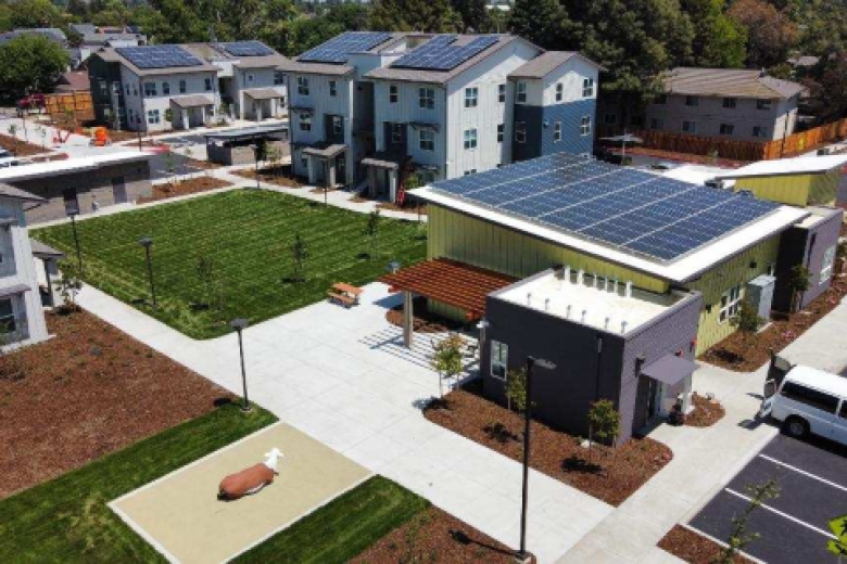 Various new multifamily housing units with solar PV on roofs with focus on community building and lawn area between units